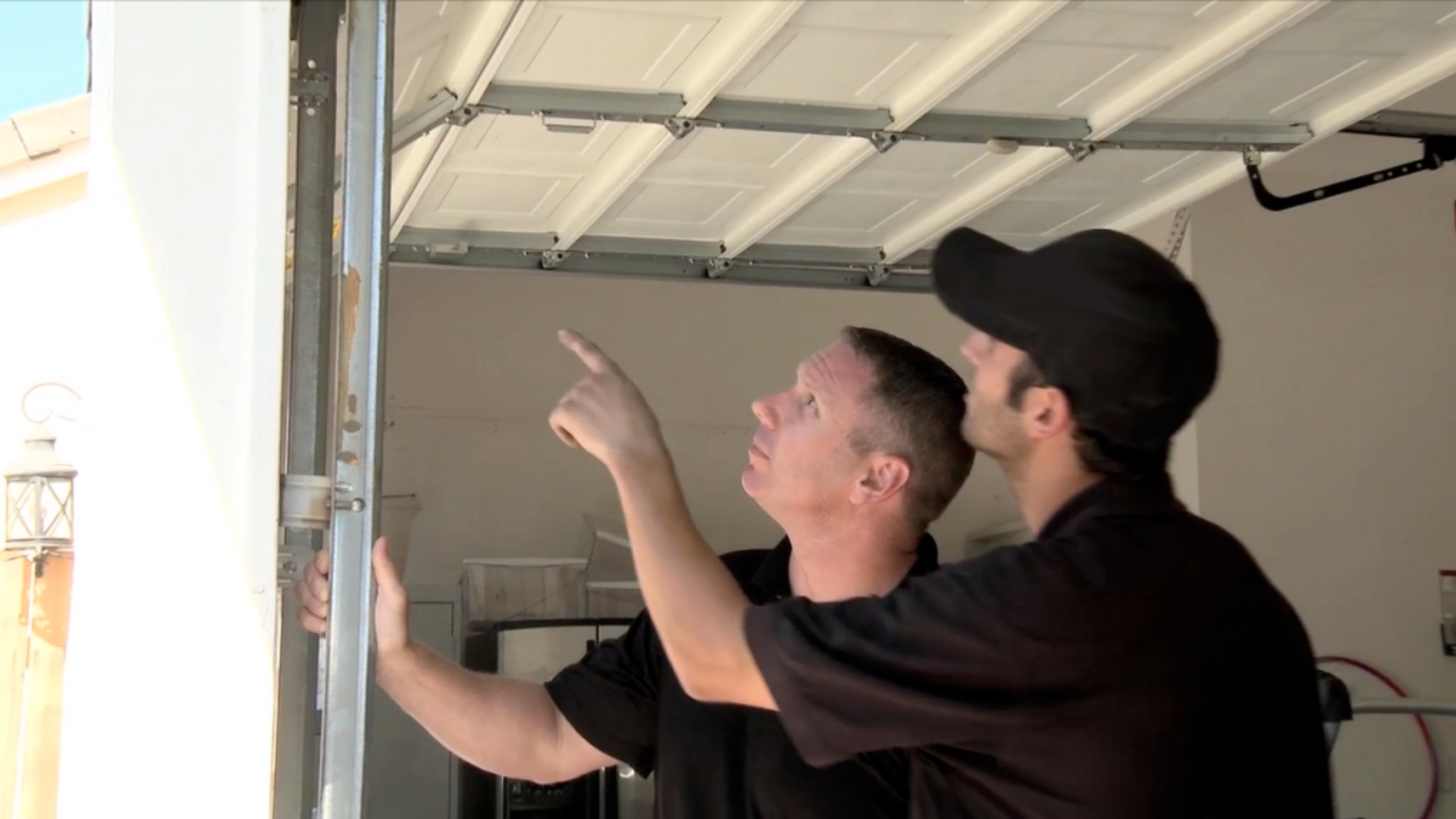 Two garage door technicians inspecting the garage door