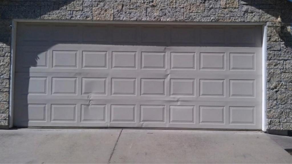 Visible dents in garage door panels from vehicle impact or stress