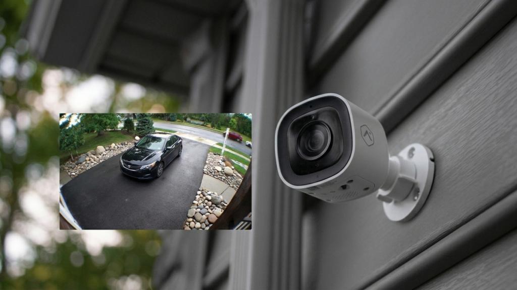 Outdoor security camera mounted beside a garage, showing a driveway view to monitor vehicles and improve home garage door security.