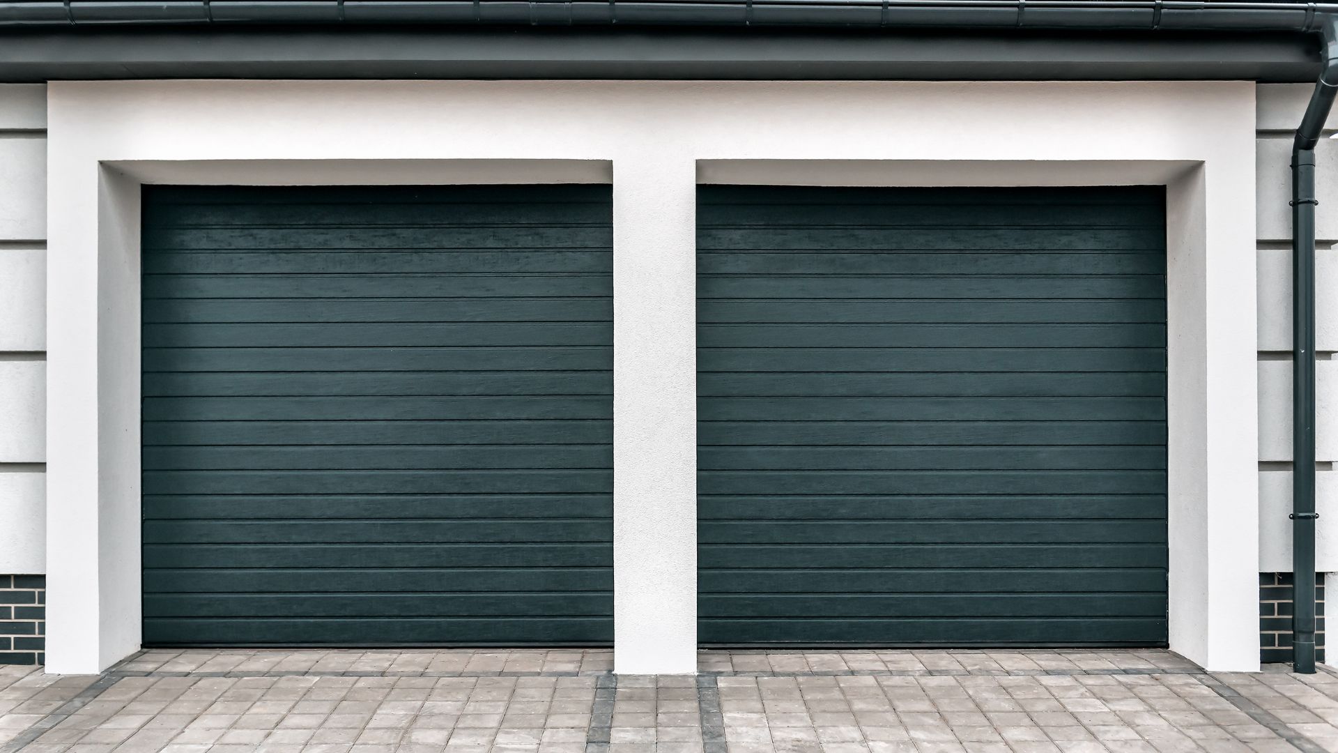 Two modern black single garage doors installed on a contemporary residential home exterior in Omaha, NE