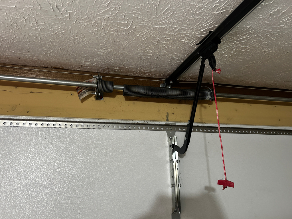 Torsion spring mechanism and opener arm assembly above garage door for garage door spring replacement.